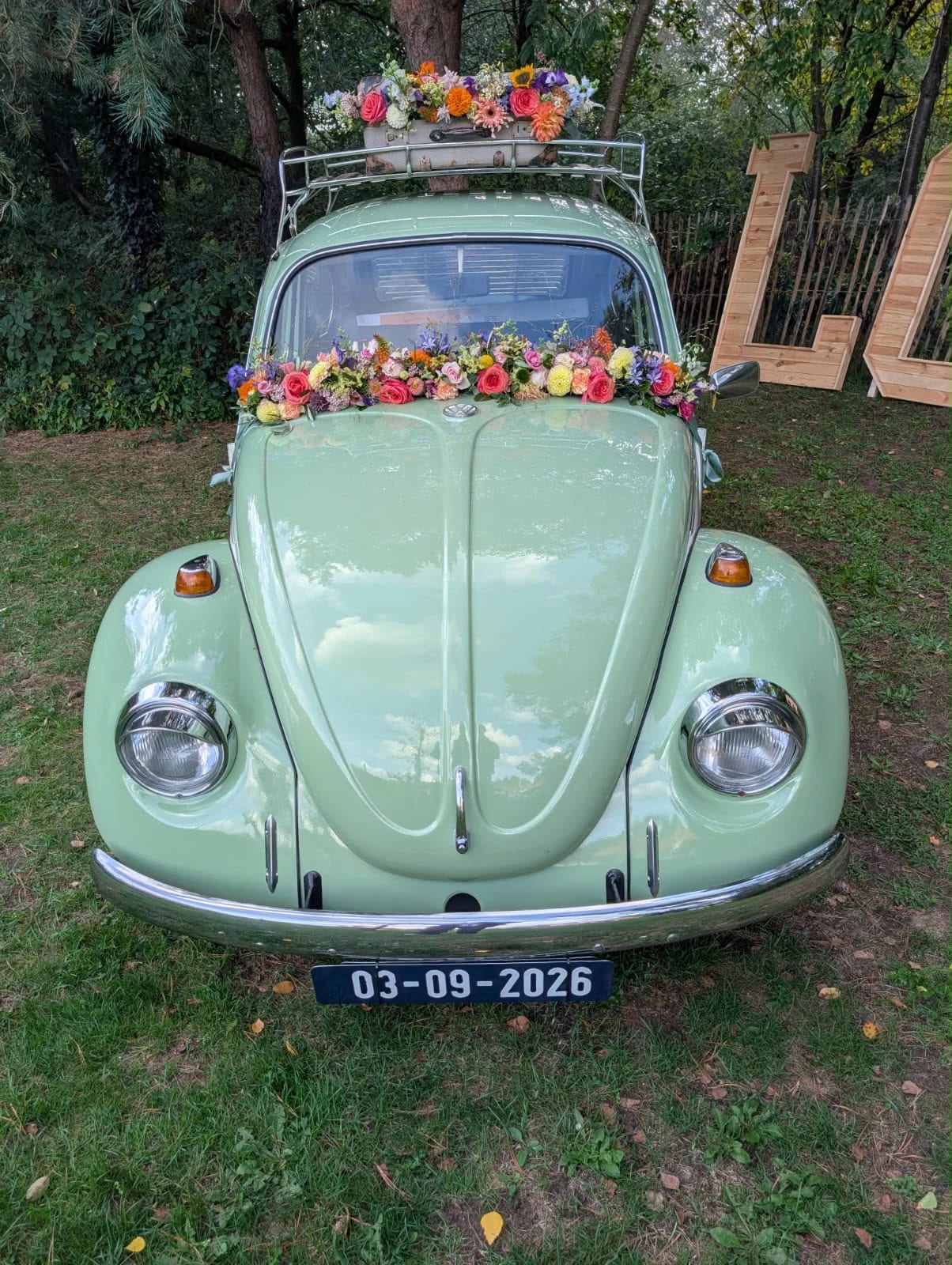 Groene trouwauto met kleurrijke bloemen op de motorkap en het dak