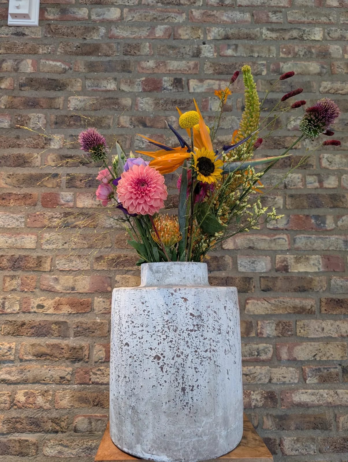 Veldachtig arrangement van echte bloemen in een witte vaas